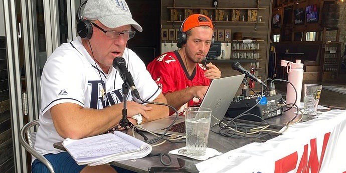 A photo of Anthony Pellegrino, a Saint Leo University sport business degree alum, with JP Peterson in a radio station studio hosting the JP Peterson Show on 820 WWBA-AM in Tampa