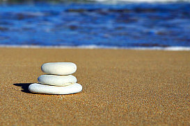 white rocks stacked on sand with water in background
