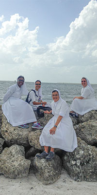 A photo showing Sr. Mary Jackson, who completed a master's in education from Saint Leo University, on the beach with her fellow Salesian Sisters