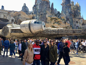 A photo showing several students in Saint Leo University's Star Wars class visiting 'Star Wars: Galaxy's Edge' at Disney World where they are standing in front of the Millennium Falcon
