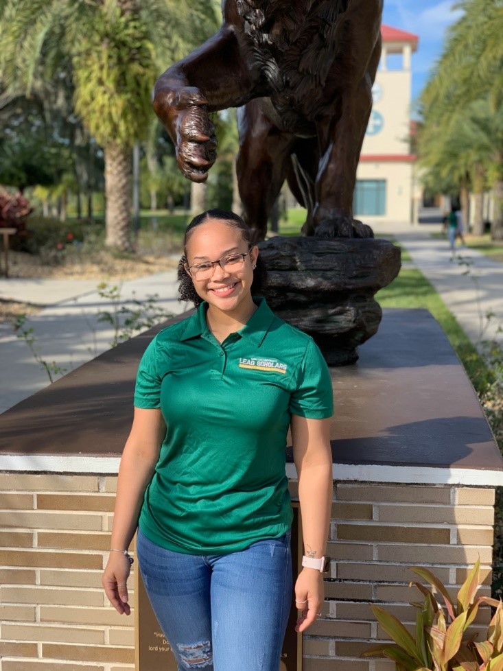 A photo of Tracey Sands, a student in Saint Leo University's 3+1 Marketing to MBA accelerated degree program, standing in front of the lion statue on University Campus