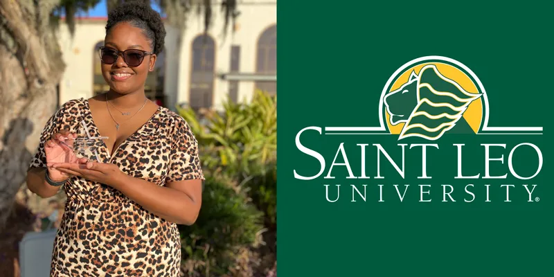 A photo of Ashley Griffith, an international hospitality management degree student at Saint Leo University, standing outside at University Campus holding her 'Outstanding Junior' award which she received in the spring of 2022; she is wearing a dress and sunglasses and smiling