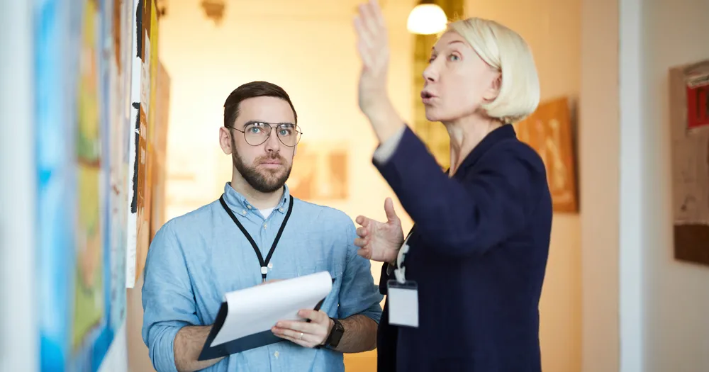 A photo of a female curator in an art museum speaking to a man who is holding a notepad for the blog article on the best careers for history majors who earn a BA in history from Saint Leo University