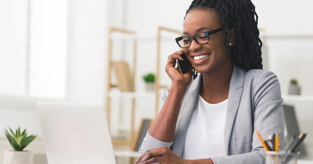 A young African American woman dressed nicely talking on a cell phone for the blog article on negotiating a job offer for a new position
