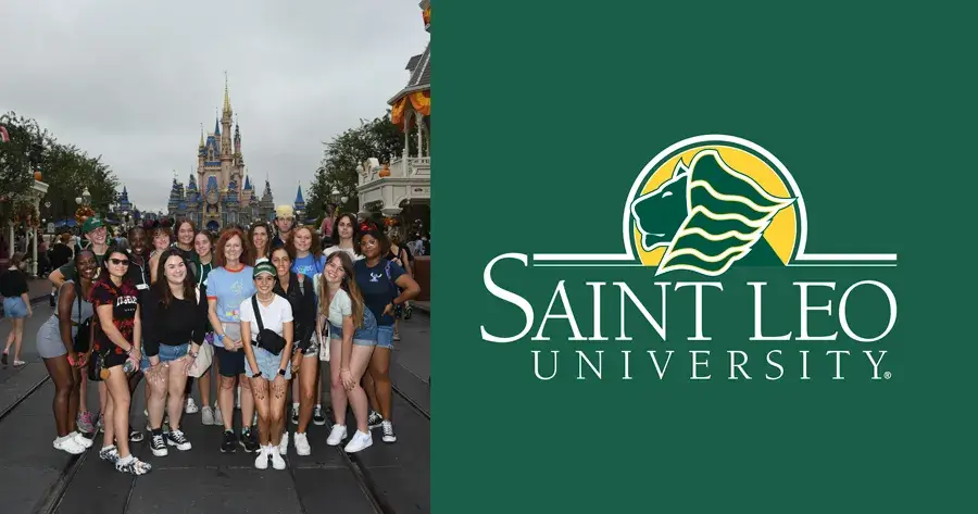 A group photo of 16 students with professor Dr. Kathryn Duncan from the class on Disney literature at Saint Leo University posing in front of the Magic Kingdom castle theme park in Orlando in October of 2022