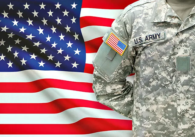 Military member standing in front of flag