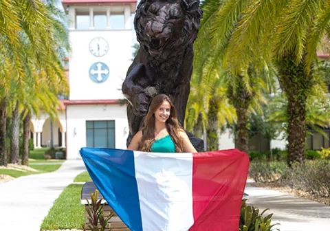 International student stands near the lion statue on campus