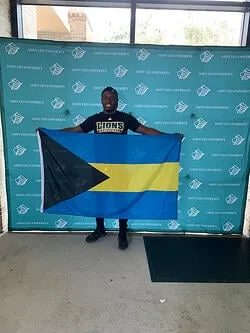 A photo of Cornelius Clyde, a Saint Leo University computer science degree major, holding the Bahamian flag representing his home country