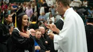 Father Randall Meissen blesses student and distributes Communion