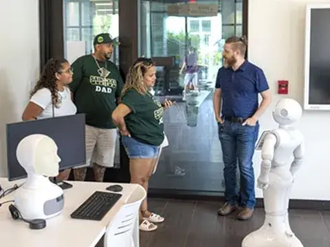 Incoming student and parents with Dr. Adams and robot in Robotics and AI lab