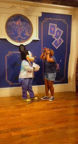 A photo of Doriann Pina, a student in the class on Disney literature this fall at Saint Leo University, posing with a man dressed up as Mickey Mouse at the Magic Kingdom theme park in Orlando in October of 2022