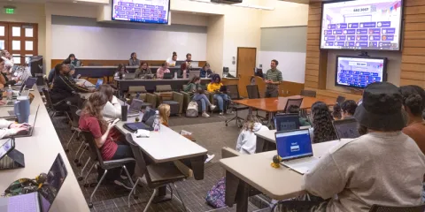 A photo from the Saint Leo University honors class Wild Florida from the fall of 2022 in TECO Hall showing two of the three professors who team taught the course; Dr. Timothy Jussaume is standing in front of a screen, and Dr. Allyson Marino is sitting down at the front of the classroom; not pictured is Prof. Gianna Russo who taught the other section of the course with Jussaume