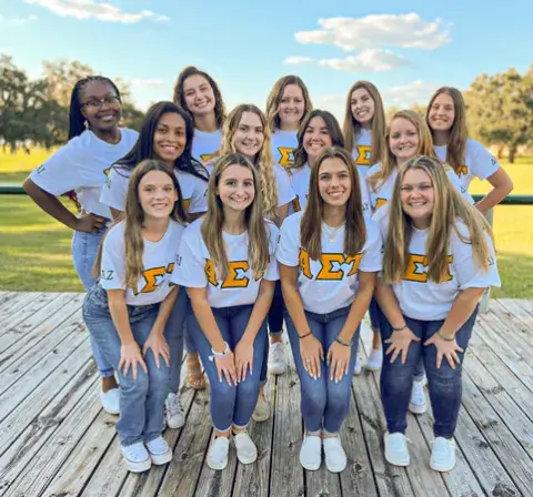 A photo of Allyson Musser, a senior BS in accounting major at Saint Leo University, posing with 12 other female students wearing 'Alpha Sigma Tau' sorority t-shirts by the bowl at University Campus; Musser served as president of the Delta Upsilon chapter of Alpha Sigma Tau at Saint Leo from August of 2021 to December 2022