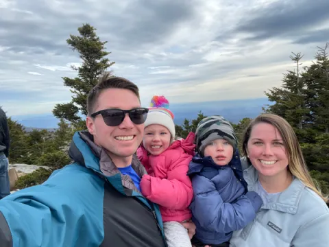 A photo of James “Dakota” Swonger, an alumnus of Saint Leo University and the Saint Leo ROTC program, posing with his family; this includes his wife, Alex; daughter, Avery; and son, Landon