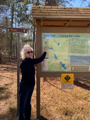 A photo of Deb Adams, a 1996 alumna of the Saint Leo business administration degree program, pointing at a map on Tate’s Trail which is part of the Carolina Sandhills National Wildlife Refuge
