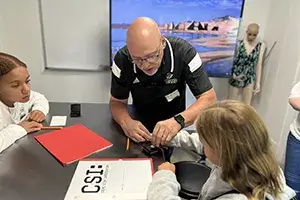 Dr. Bill Elders shows middle school students how to fingerprint someone